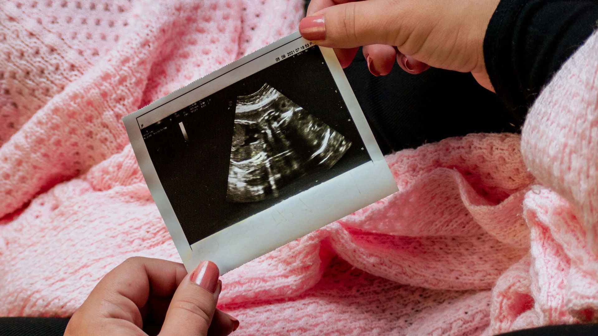 Mani di neonato su una coperta rosa